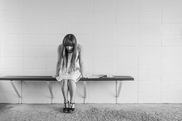 Girl sitting down and looking down to the floor